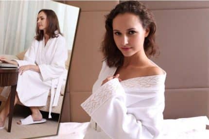 Mujer con bata de felpa blanca en habitación de hotel de lujo